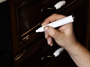 Furniture marker restoration of wooden furniture the master fixes a scratch on the facade